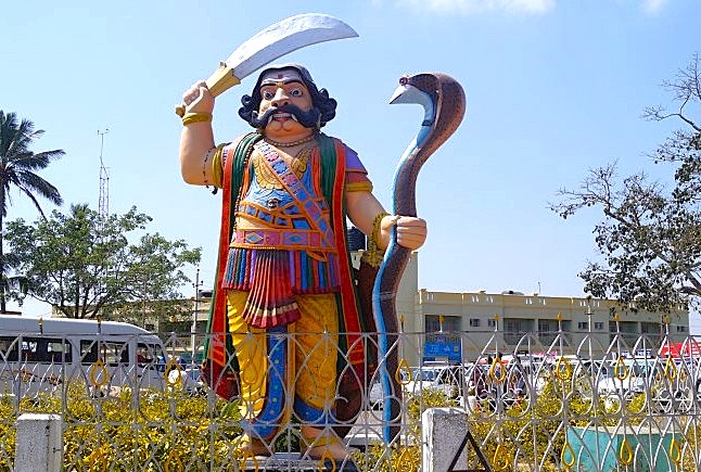 “Vibrant mythological statue of Mahishasura at Chamundi Hill in Mysore, Karnataka, India, showcasing traditional craftsmanship and cultural heritage against an iconic serene outdoor temple backdrop.”