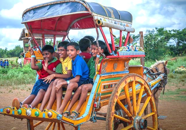 Smiling children enjoy a colorful horse carriage ride at Agadi Thota Village in Hubli, Karnataka, India, a fun family stop on the way to Old Goa Unesco churches.
