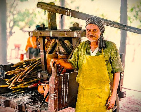 A man prepares fresh sugarcane juice for visitors at Agadi Thota Village in Hubli, Karnataka, India, a cultural stop on the way to the Old Goa Unesco churches.