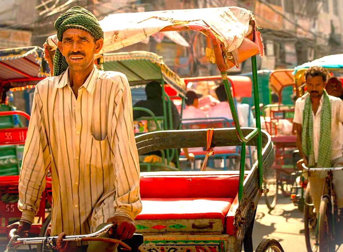 A rickshaw cyclist navigates the bustling streets of Delhi, India, a common sight near the vibrant Chandni-chowk-spice-market and historical UNESCO sites like the Red Fort and Humayun's Tomb.