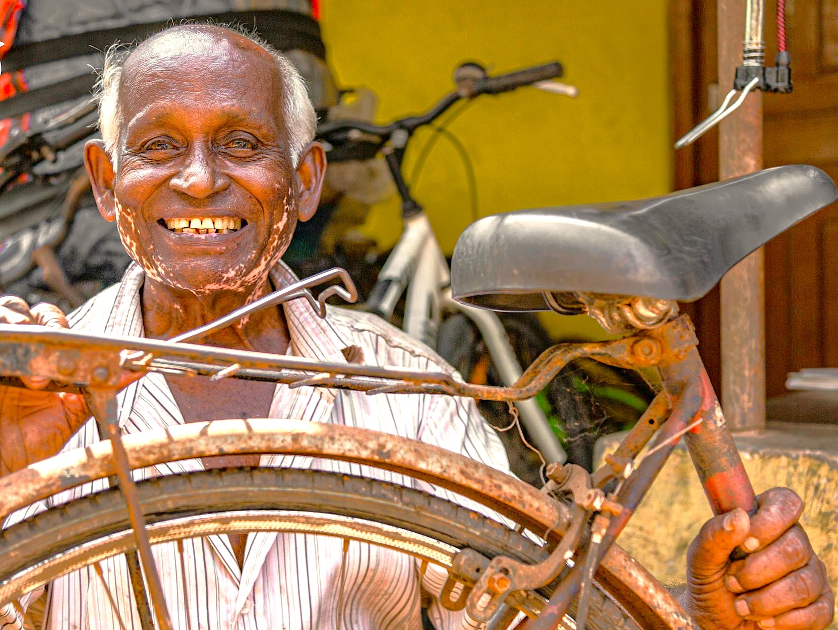Cheerful elderly bicycle mechanic repairs vintage bike amid Ajanta and Elora Caves tourist area near Aurangabad, Maharashtra, India at a UNESCO heritage site workshop blending nostalgia, craftsmanship and cultural significance.