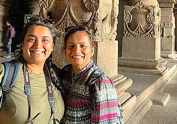 Two cheerful women pose before the intricately carved walls of Alamgir Dargah in Aurangabad, Maharashtra, India, near UNESCO World Heritage Elora and Ajanta Caves, showcasing cultural heritage tourism and smiling.