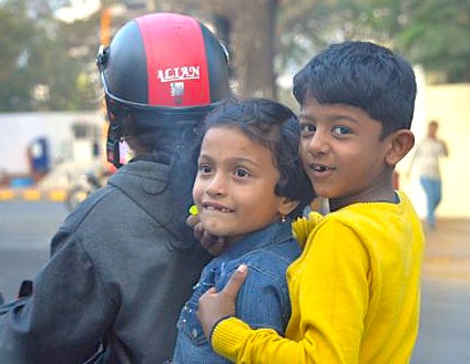 “Two smiling children hug on a motorbike outside Alamgir Dargah in Aurangabad, Maharashtra, India, symbolizing joyous local culture against a UNESCO backdrop near the Ellora and Ajanta Caves pilgrimage sites.”