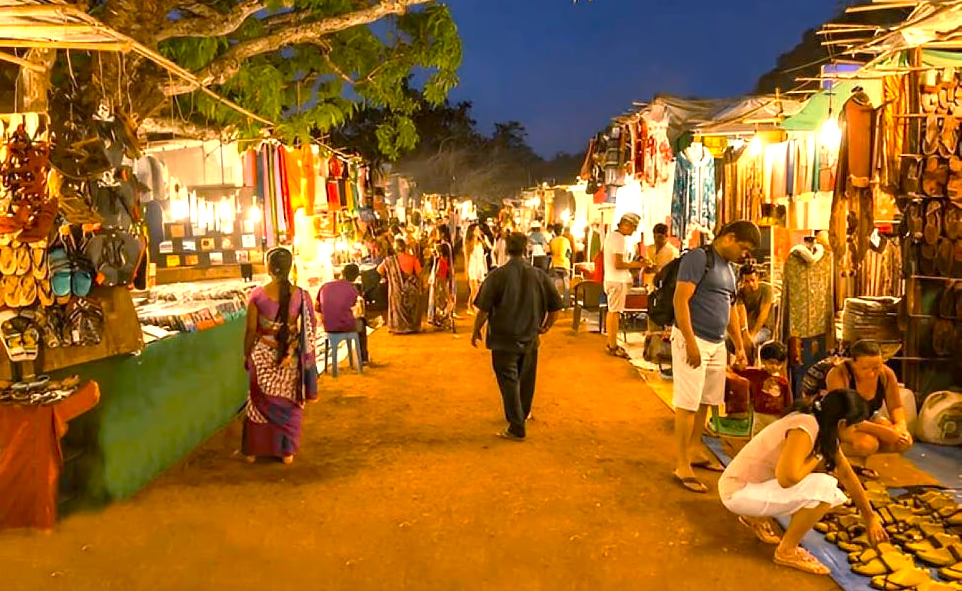 Tourists browse stalls at the illuminated Anjuna Beach Flee Market, a famous part of the Goa Beaches experience in India, located near Karnataka and the historic Old Goa St. Francis Church UNESCO churches. Tourists browse stalls at the illuminated Anjuna Beach Flee Market, a famous part of the Goa Beaches experience in India, located near Karnataka and the historic Old Goa St. Francis Church UNESCO churches.