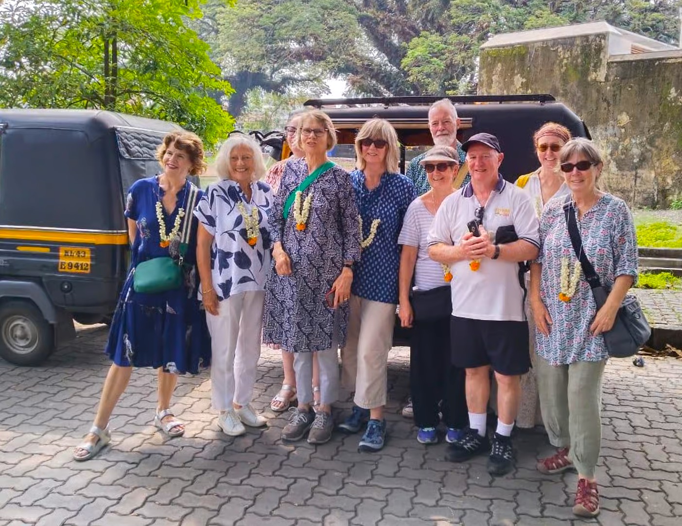 Cheerful group of travelers wearing floral garlands pose beside a traditional auto rickshaw against lush Aravali Hills backdrop near Jodhpur, Rajasthan, India, capturing vibrant cultural celebration and shared scenic joy. Cheerful group of travelers wearing floral garlands pose beside a traditional auto rickshaw against lush Aravali Hills backdrop near Jodhpur, Rajasthan, India, capturing vibrant cultural celebration and shared scenic joy.