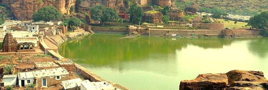 A panoramic view shows the sacred Agastya Lake in Badami, Karnataka, India, with ancient stone temples and ghats lining its banks beneath dramatic sandstone cliffs. This historic reservoir is a key feature of the heritage town, located near the Pattadakal UNESCO World Heritage site. A panoramic view shows the sacred Agastya Lake in Badami, Karnataka, India, with ancient stone temples and ghats lining its banks beneath dramatic sandstone cliffs. This historic reservoir is a key feature of the heritage town, located near the Pattadakal UNESCO World Heritage site.