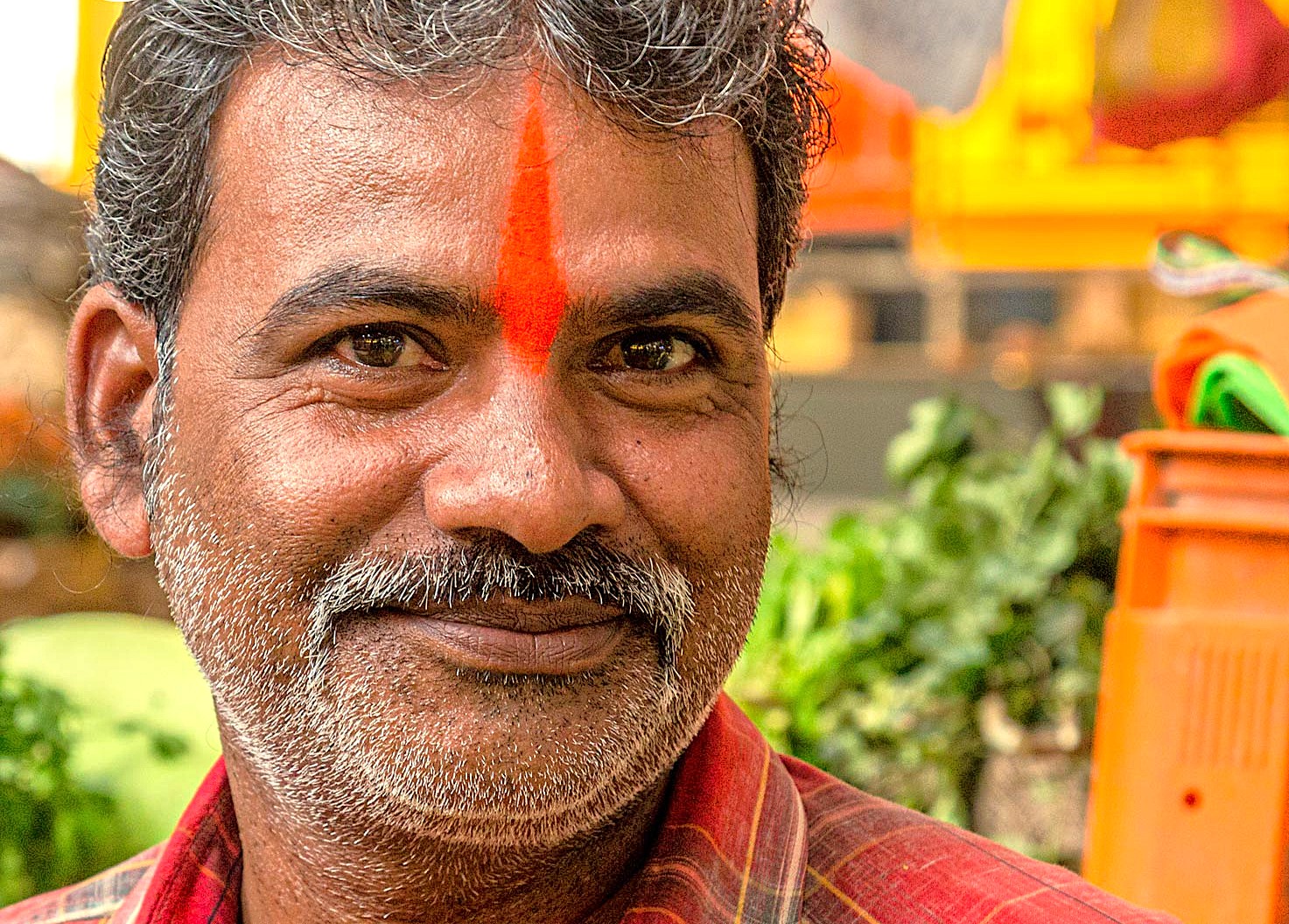 “Smiling middle-aged Indian vendor with traditional tilak in a vibrant Maharashtra outdoor market during the Aurangabad Railway journey from Mumbai to UNESCO-listed Elora and Ajanta Caves, highlighting historic cultural heritage.”