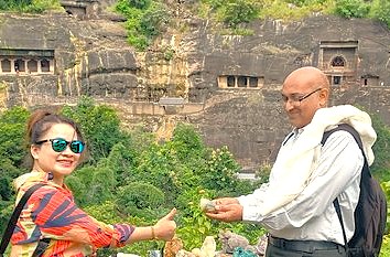 Two tourists exchange an authentic souvenir at the ancient UNESCO-listed Ellora Caves in Aurangabad, Maharashtra, as part of the picturesque Mumbai–Aurangabad railway journey to Elora and Ajanta Caves in India.