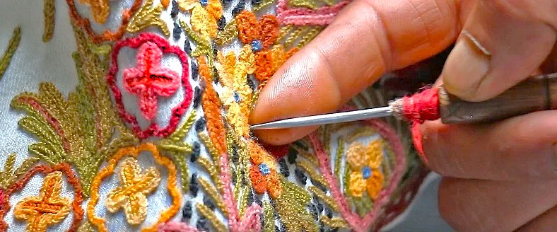 A skilled artisan demonstrates intricate Kashmiri embroidery at Babu Arts and Craft Emporium in Srinagar, Jammu, a destination near saffron fields, Aru Valley, and Betaab Valley.
