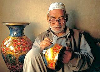 A Kashmiri artisan at Babu Arts and Craft Emporium in Srinagar, Jammu, paints papier-mâché, a traditional craft near saffron fields, Aru Valley, and Betaab Valley.