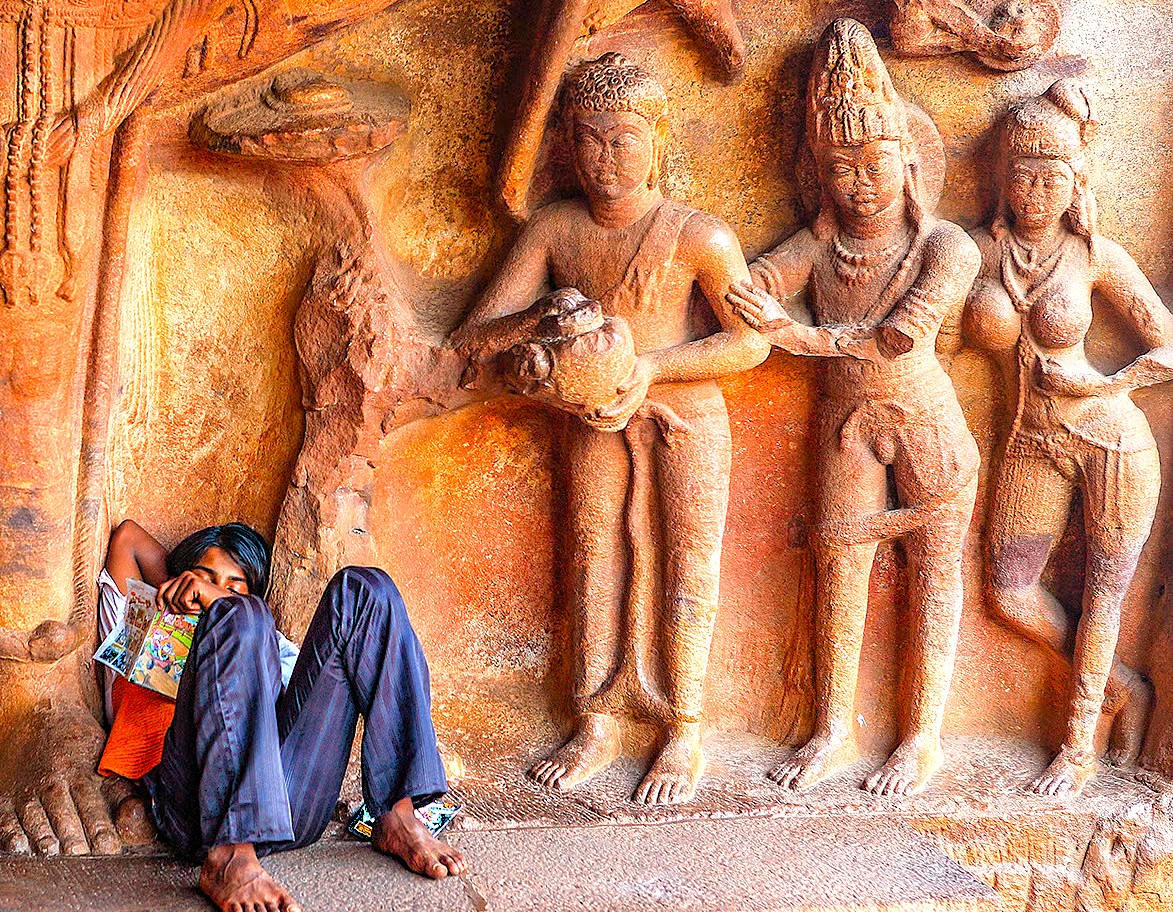 A local man rests at the base of intricate Chalukyan-era sandstone carvings at Badami Fort in Karnataka, India, a major heritage site located near the Pattadakal UNESCO complex. A local man rests at the base of intricate Chalukyan-era sandstone carvings at Badami Fort in Karnataka, India, a major heritage site located near the Pattadakal UNESCO complex.