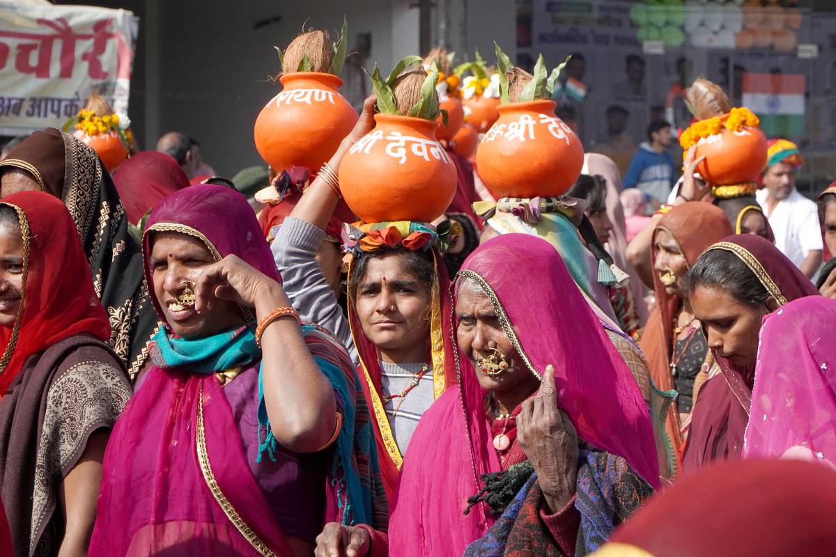 Vibrant festival procession at Bagore Ki Haveli Museum in Udaipur, Rajasthan, India features women in colorful sarees balancing decorated pots, celebrating rich Rajasthani traditions, unity, cultural heritage, and joyous rituals.