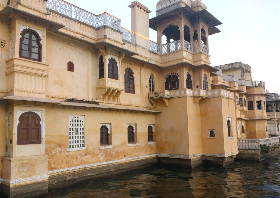 The majestic Bagore Ki Haveli Museum in Udaipur, Rajasthan, India perches on Lake Pichola’s edge, featuring ornate Rajput architecture, carved jharokhas, heritage exhibits, colorful cultural murals, and panoramic waterfront views.