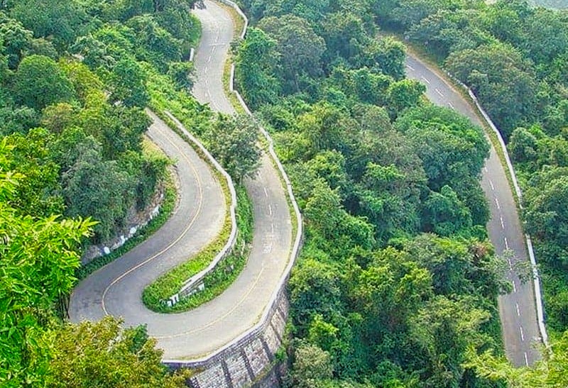 Winding mountain road in India passing through Madurai and Munnar, states Kerala and Tamil Nadu road trip, surrounded by dense forested hills offering scenic adventure.