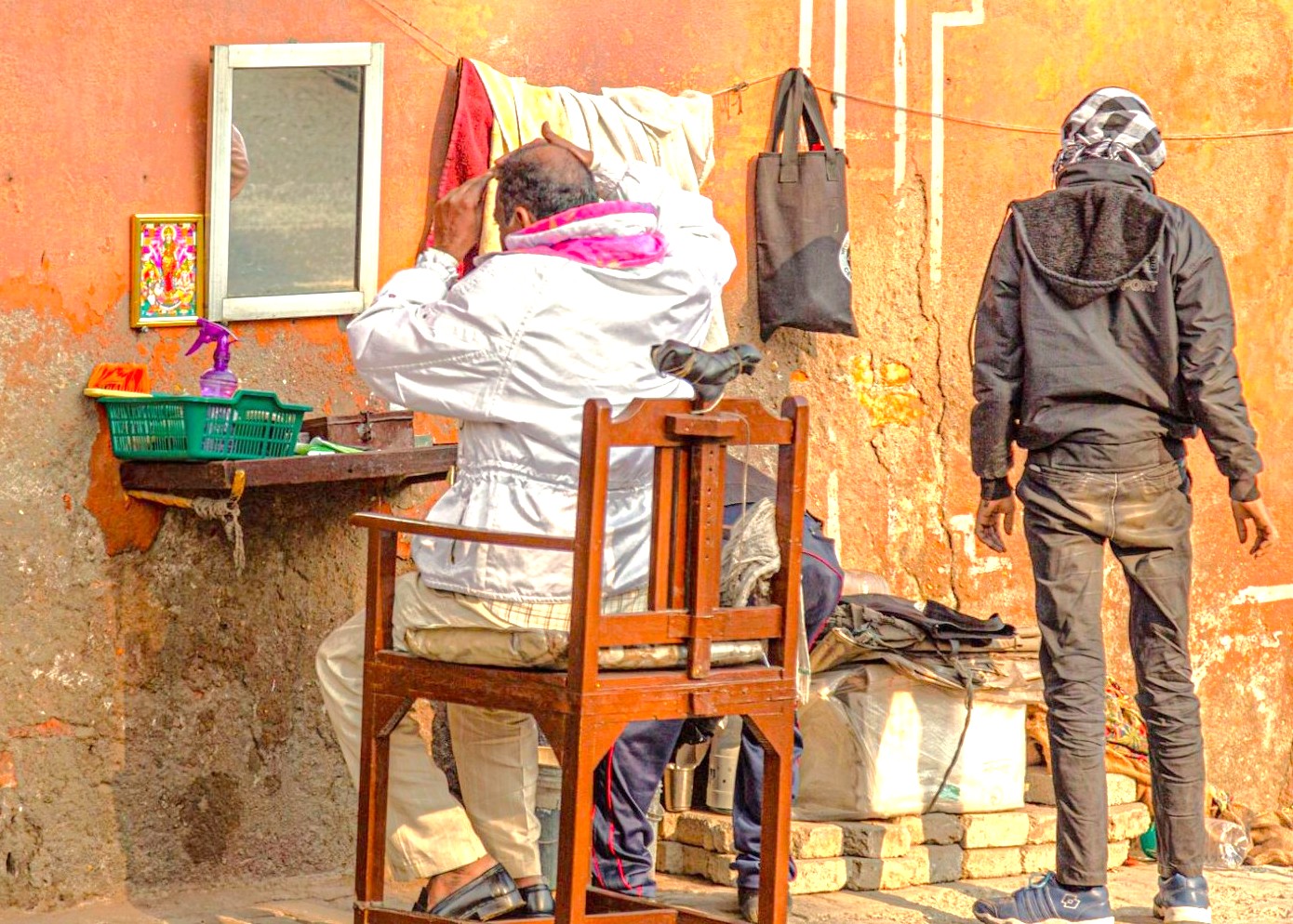 The trusting relationship between a barber and client at an outdoor shop offers an authentic cultural sight on the Mumbai to Aurangabad railway journey in India, a route for tourists visiting Unesco's Ellora, Ajanta Caves, and the Elephanta Caves.