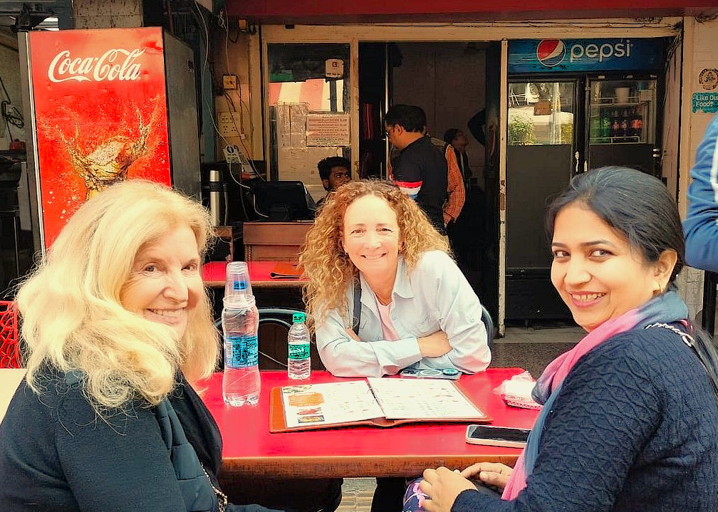 "Happy female travelers and local guide sharing a meal in Kashmir, India, representing safe, comfortable small group tours in Srinagar, Aru and Beetab Valleys."