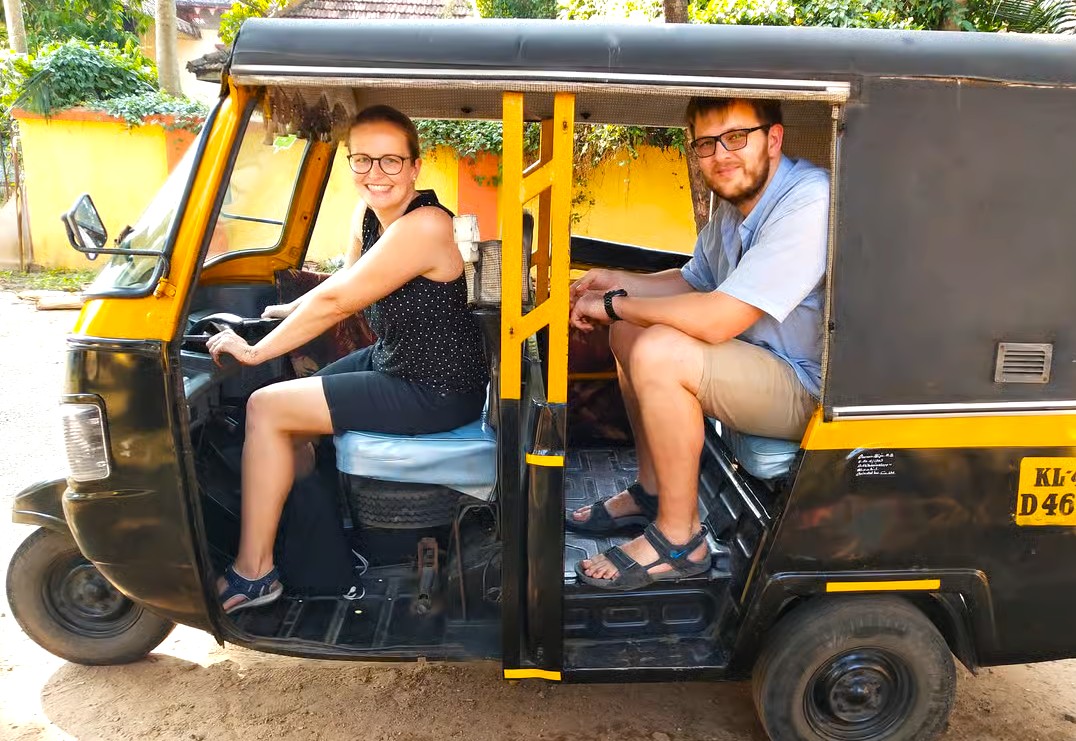 Two tourists ride a vibrant auto rickshaw through Bikaner, Rajasthan, India, en route to the historic Bhandasar Jain Temple, with golden Thar Desert landscapes unfolding beyond storied ancient city walls. Two tourists ride a vibrant auto rickshaw through Bikaner, Rajasthan, India, en route to the historic Bhandasar Jain Temple, with golden Thar Desert landscapes unfolding beyond storied ancient city walls.