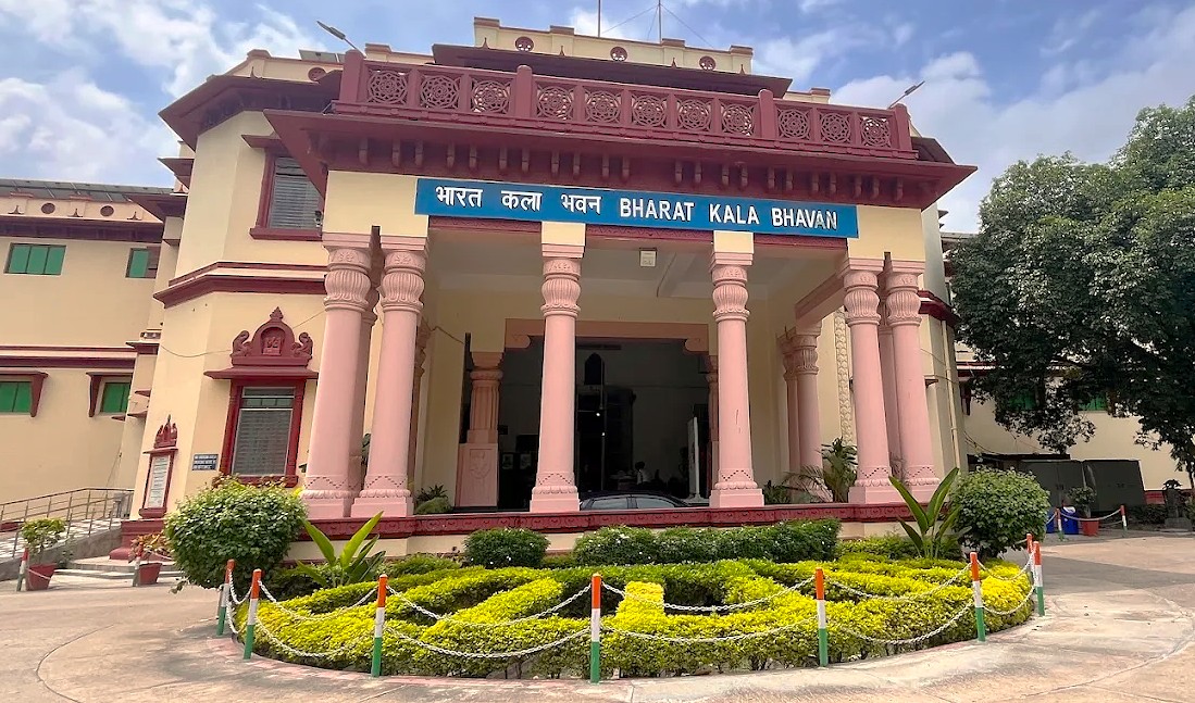 “Facade of the Bharat Kala Bhavan Museum in Varanasi, Uttar Pradesh, India, near Sarnath Temple Buddha, showcases traditional Indian architecture with ornate pillars, decorative landscaping, and cultural exhibits celebrating heritage.”