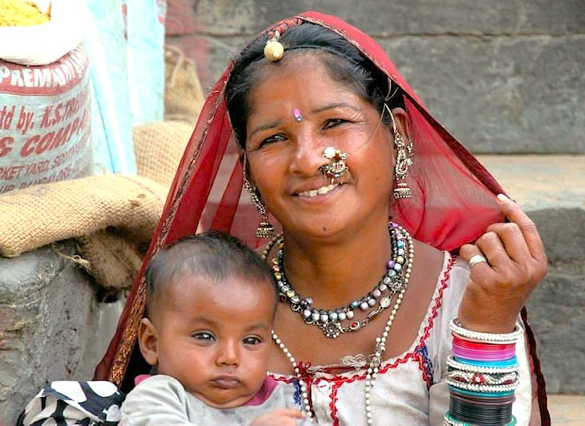 Smiling rural Maharashtrian mother cradles infant amidst stone steps near Bibi Ka Maqbara in Aurangabad, Maharashtra, reflecting India’s cultural heritage and traditional attire, evocative of UNESCO-listed Ellora and Ajanta Caves.