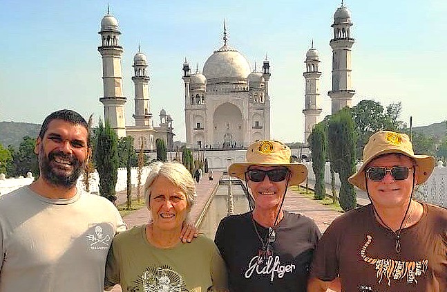 Group of four smiling tourists pose at Bibi Ka Maqbara in Aurangabad, Maharashtra, India, gateway to UNESCO Ellora and Ajanta Caves, highlighting cultural travel, heritage exploration, and friendly tour experience.