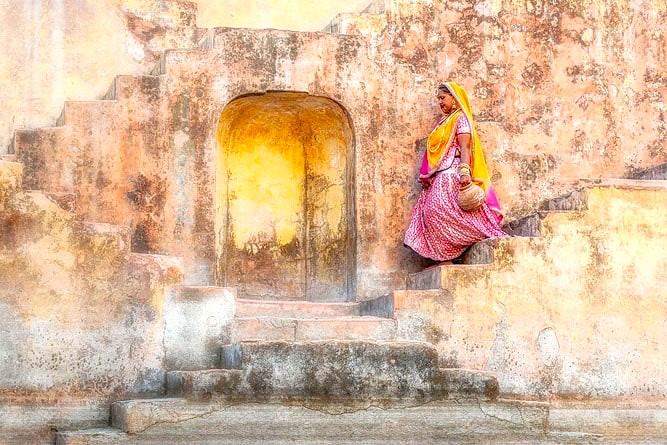 “Serene woman in traditional attire at Chand Baori step well in Rajasthan, India, near Uttar Pradesh, highlighting ancient stone architecture, cultural heritage, and tranquil atmosphere.”