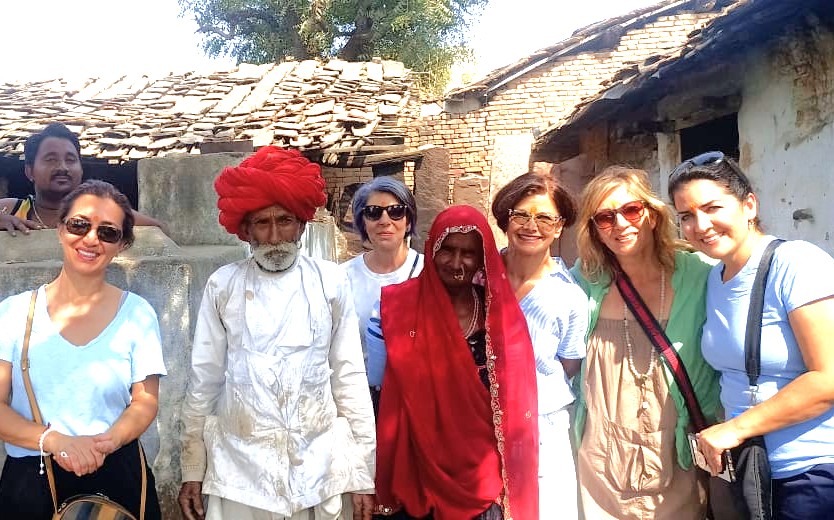 Group of enthusiastic travelers visiting Chand Baori step well in Rajasthan, India, near Uttar Pradesh border, enjoying cultural heritage tour, rustic village setting, smiling faces.