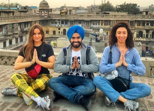 Three global travelers sit cross-legged on a rooftop overlooking historic India-Chandi Chowk Spice Market Old Delhi, exchanging namaste, celebrating cultural unity, vibrant heritage, spiritual connection, and dynamic panoramic urban energy. Three global travelers sit cross-legged on a rooftop overlooking historic India-Chandi Chowk Spice Market Old Delhi, exchanging namaste, celebrating cultural unity, vibrant heritage, spiritual connection, and dynamic panoramic urban energy.