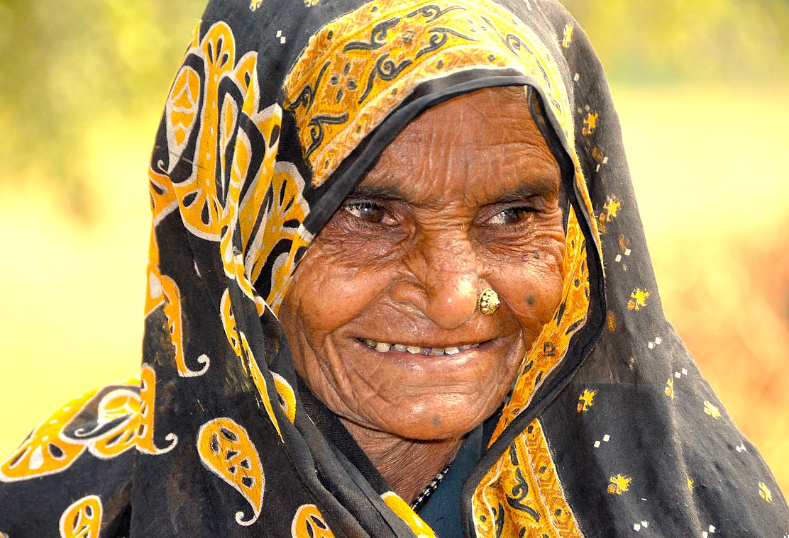 A close-up portrait of a smiling elderly local woman in traditional attire, reflecting the culture near Chinar Bagh Ghat in Srinagar, Jammu and Kashmir, India.