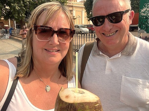 Smiling tourists enjoy fresh coconut water while visiting Chinar Bagh Ghat, a popular travel spot for sightseeing in Srinagar, Jammu and Kashmir, India.