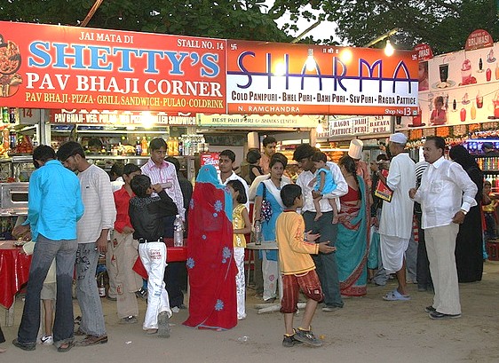 Vibrant street food scene at Shetty’s Pav Bhaji Corner on Chowpatty Beach in Mumbai, Mahapradesh, India showcases colorful stalls, diverse crowd enjoying spicy pav bhaji, grilled sandwiches, cultural culinary experience.