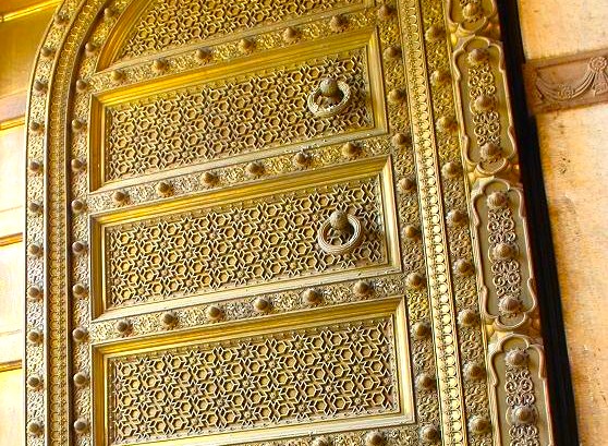 Ornate golden door panels at Jaipur’s City Palace, Rajasthan, India, showcase intricate geometric motifs influenced by Islamic art, reflecting UNESCO heritage status and historic craftsmanship in the royal architectural complex.