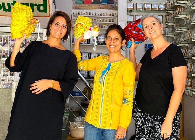 Three smiling women pose with vibrant handcrafted souvenir bags in a bustling Udaipur shop near City Palace, Rajasthan, India, highlighting authentic local markets, rich cultural heritage, and skilled artisanal craftsmanship. Three smiling women pose with vibrant handcrafted souvenir bags in a bustling Udaipur shop near City Palace, Rajasthan, India, highlighting authentic local markets, rich cultural heritage, and skilled artisanal craftsmanship.