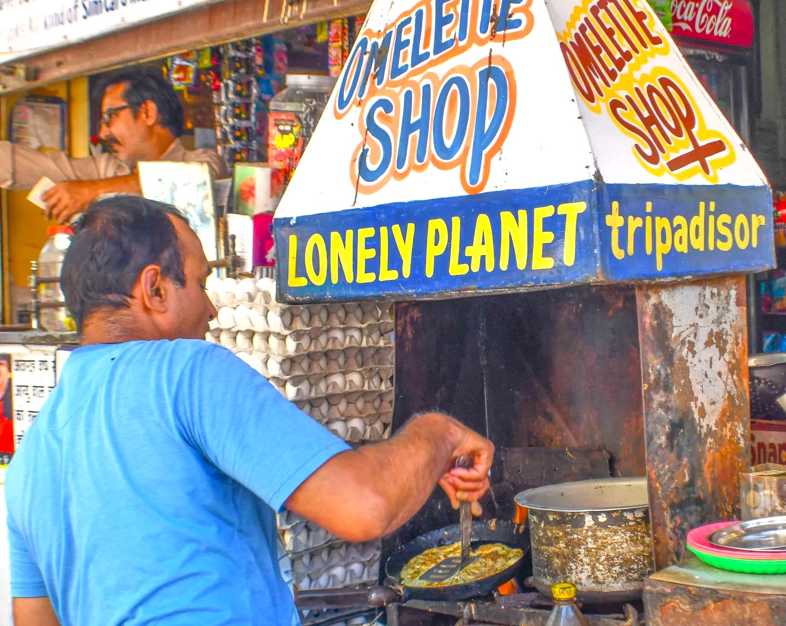 “Skilled street food vendor fries an omelette at a bustling stall under the Clockwork Tower in Jodhpur, the Blue city of Rajasthan, India, inviting visitors to taste authentic local flavors.”  “Skilled street food vendor fries an omelette at a bustling stall under the Clockwork Tower in Jodhpur, the Blue city of Rajasthan, India, inviting visitors to taste authentic local flavors.”