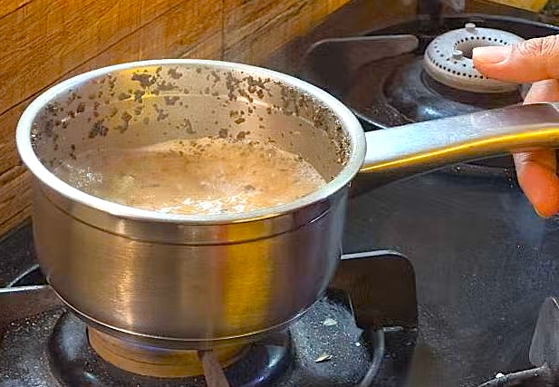 A person stirs chai in a saucepan on a gas stove during authentic India cooking classes in Coimbatore, Tamil Nadu, near Patteeswara Temple, learning traditional methods. A person stirs chai in a saucepan on a gas stove during authentic India cooking classes in Coimbatore, Tamil Nadu, near Patteeswara Temple, learning traditional methods.