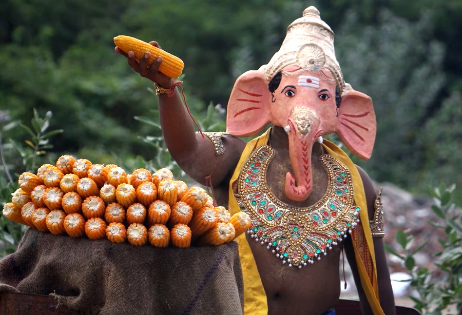 "Person in Ganesha costume holding corn, vibrant harvest scene, showcasing Indian culture and traditions, perfect for promoting India culinary experiences and authentic cooking classes in India." "Person in Ganesha costume holding corn, vibrant harvest scene, showcasing Indian culture and traditions, perfect for promoting India culinary experiences and authentic cooking classes in India."