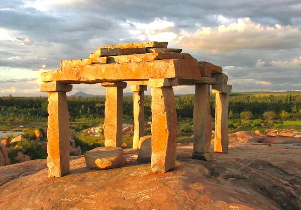“Ancient stone pavilion stands atop rugged terrain on the Deccan Plateau in Karnataka, India, bordering the UNESCO Western Ghats, offering panoramic views, cultural heritage significance, geological wonder, and serene beauty.”