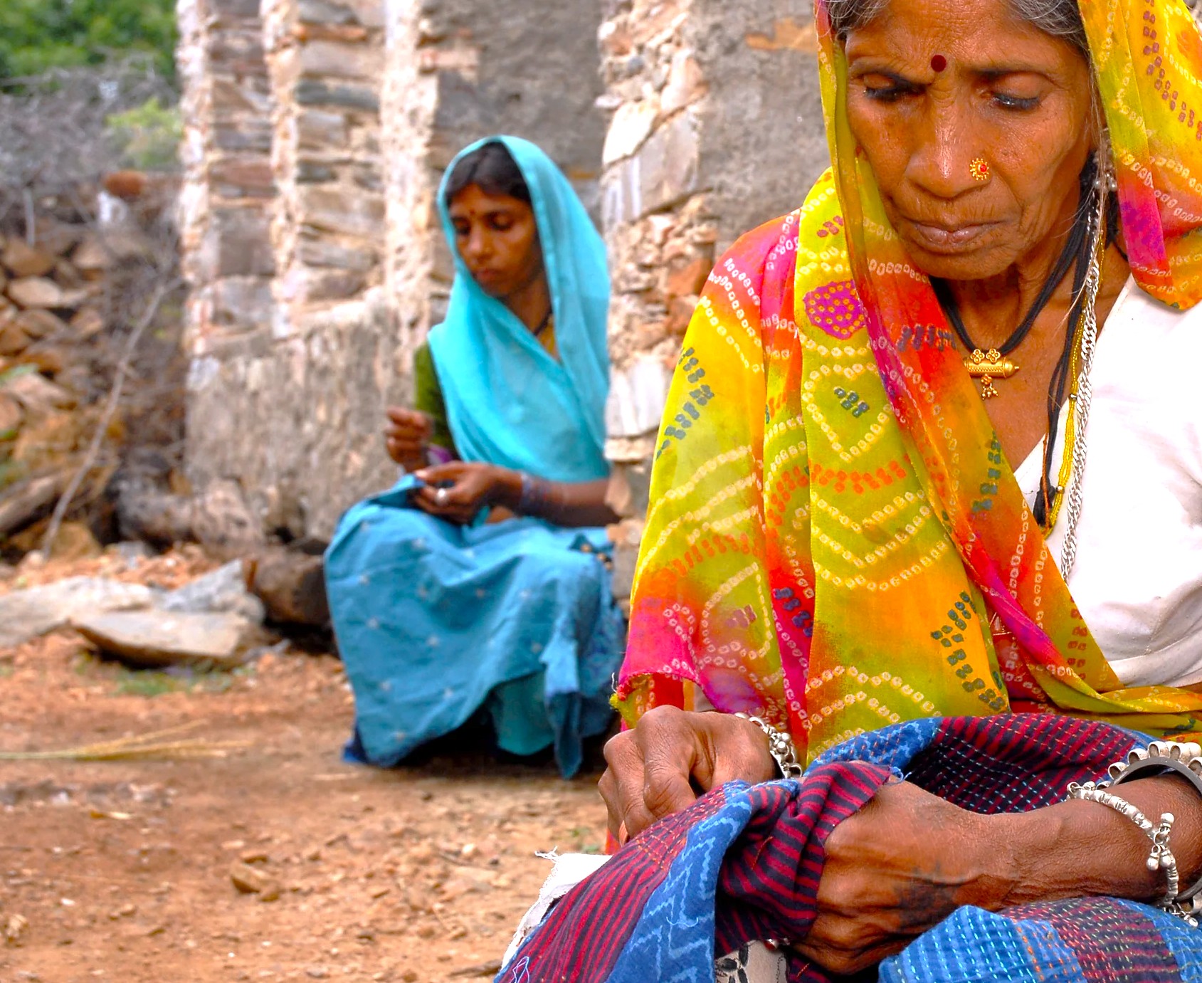Mother and daughter stitching vibrant textiles together at Delwara Handcrafts workshop, Udaipur, Rajasthan, India, preserving traditional sewing skills and empowering women artisans to overcome hardship in rural communities.