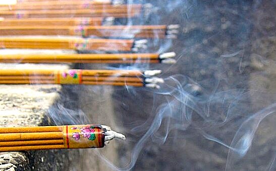 “Close-up of decorative lit incense sticks emitting smoke at Devaraja Market in Mysore, Karnataka, India.”