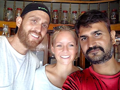Three smiling travelers enjoying herbal tea in a cozy kitchen with shelves of jars, evoking hospitality at Dodabetta Tea Plantation, Ooty, Tamil Nadu, Southern India. Three smiling travelers enjoying herbal tea in a cozy kitchen with shelves of jars, evoking hospitality at Dodabetta Tea Plantation, Ooty, Tamil Nadu, Southern India.
