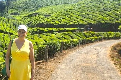 “A smiling woman in a yellow dress explores the lush tea plantations at scenic Echo Point in Munnar, Kerala, Southern India, amid rolling green hills.” “A smiling woman in a yellow dress explores the lush tea plantations at scenic Echo Point in Munnar, Kerala, Southern India, amid rolling green hills.”