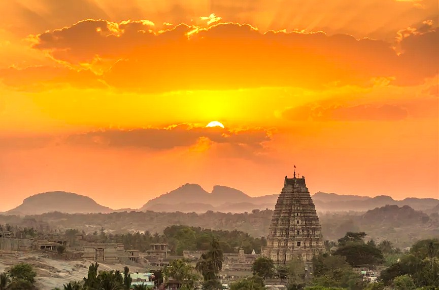 "Witness a dramatic sunset over the UNESCO ruins of Hampi in India, a stunning heritage alternative to the classic circuit of Delhi, Rajasthan, Varanassi, and a visit Unesco Taj mahal."