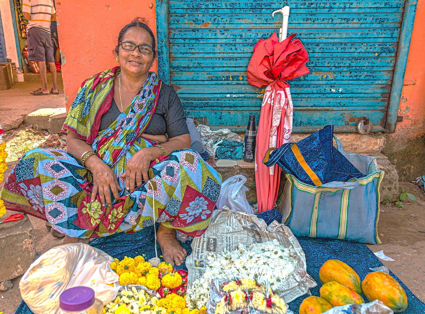 Street vendor in Maharashtra, India, sells vibrant marigolds, fragrant jasmine, colorful fabrics and fresh fruits near UNESCO World Heritage Aurangabad’s Ellora and Ajanta Caves, showcasing authentic traditional local marketplace culture.
