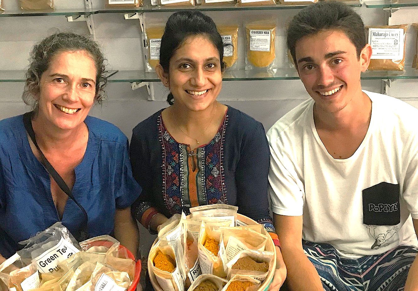 Three diverse visitors explore spice packets in Aurangabad, Maharashtra, India, near UNESCO Ellora and Ajanta Caves, during an interactive culinary workshop before embarking on a Gautala Wildlife Sanctuary safari adventure.