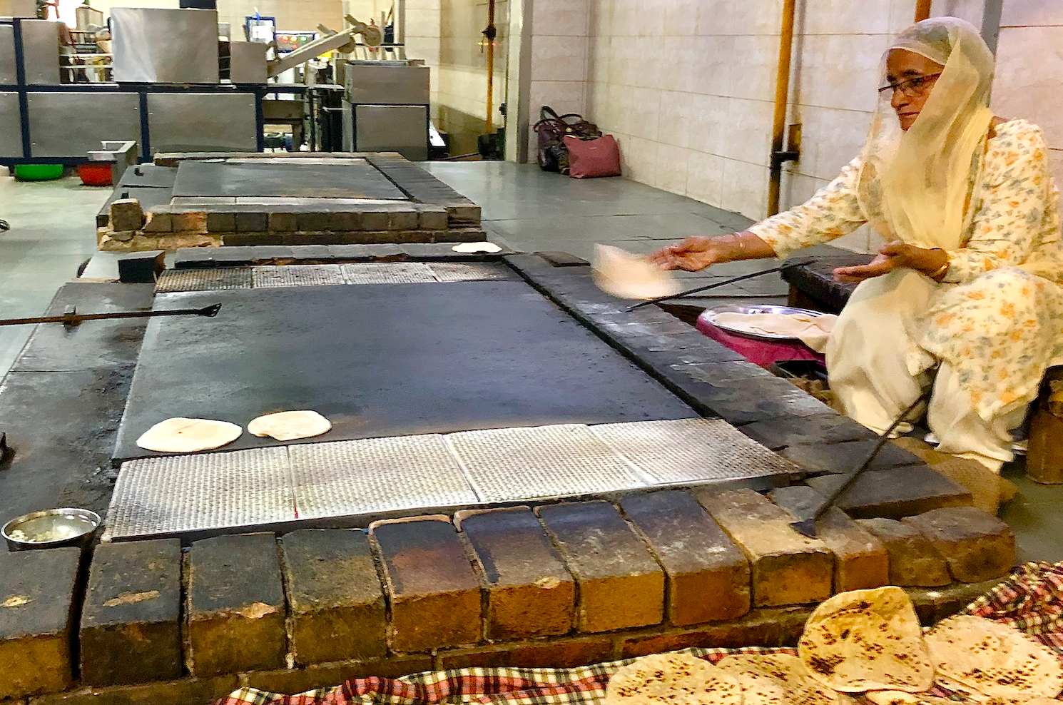 Artisan volunteer at Gurudwara Bangla Sahib Sikh Temple in New Delhi, India, daily skillfully prepares fresh chapati in the communal kitchen, showcasing centuries-old Punjabi culinary tradition and heartfelt community service. Artisan volunteer at Gurudwara Bangla Sahib Sikh Temple in New Delhi, India, daily skillfully prepares fresh chapati in the communal kitchen, showcasing centuries-old Punjabi culinary tradition and heartfelt community service.