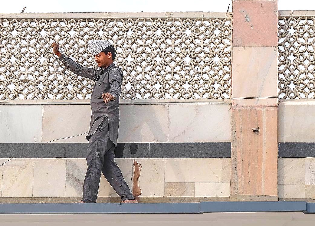 A craftsman in traditional attire restores the ornate marble façade of Gurudwara Bangla Sahib Sikh Temple in New Delhi, India, exemplifying heritage preservation, devotion and community service within sacred grounds. A craftsman in traditional attire restores the ornate marble façade of Gurudwara Bangla Sahib Sikh Temple in New Delhi, India, exemplifying heritage preservation, devotion and community service within sacred grounds.