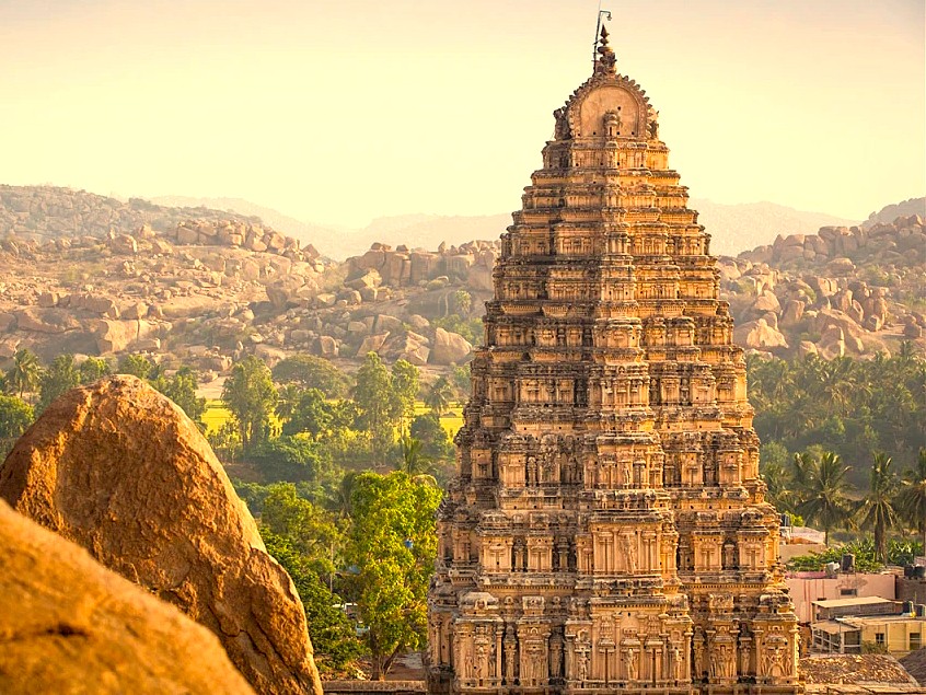 The iconic temple gopuram at the Hampi UNESCO site in Karnataka, India, stands near other famous ruins like the historic Elephant Stables and the magnificent Vittala Temple complex.