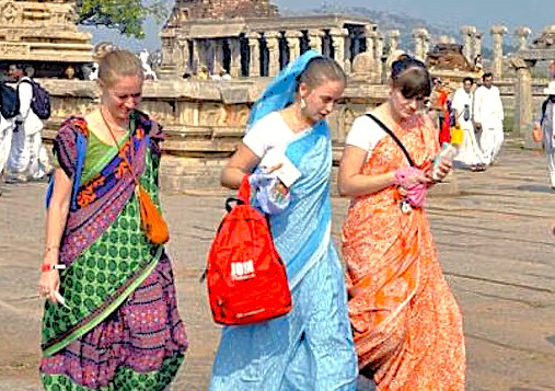 Tourists experience the ancient culture of the Hampi Unesco site in Karnataka, India, while exploring key monuments like the royal Elephant stables and the historic queens baths.