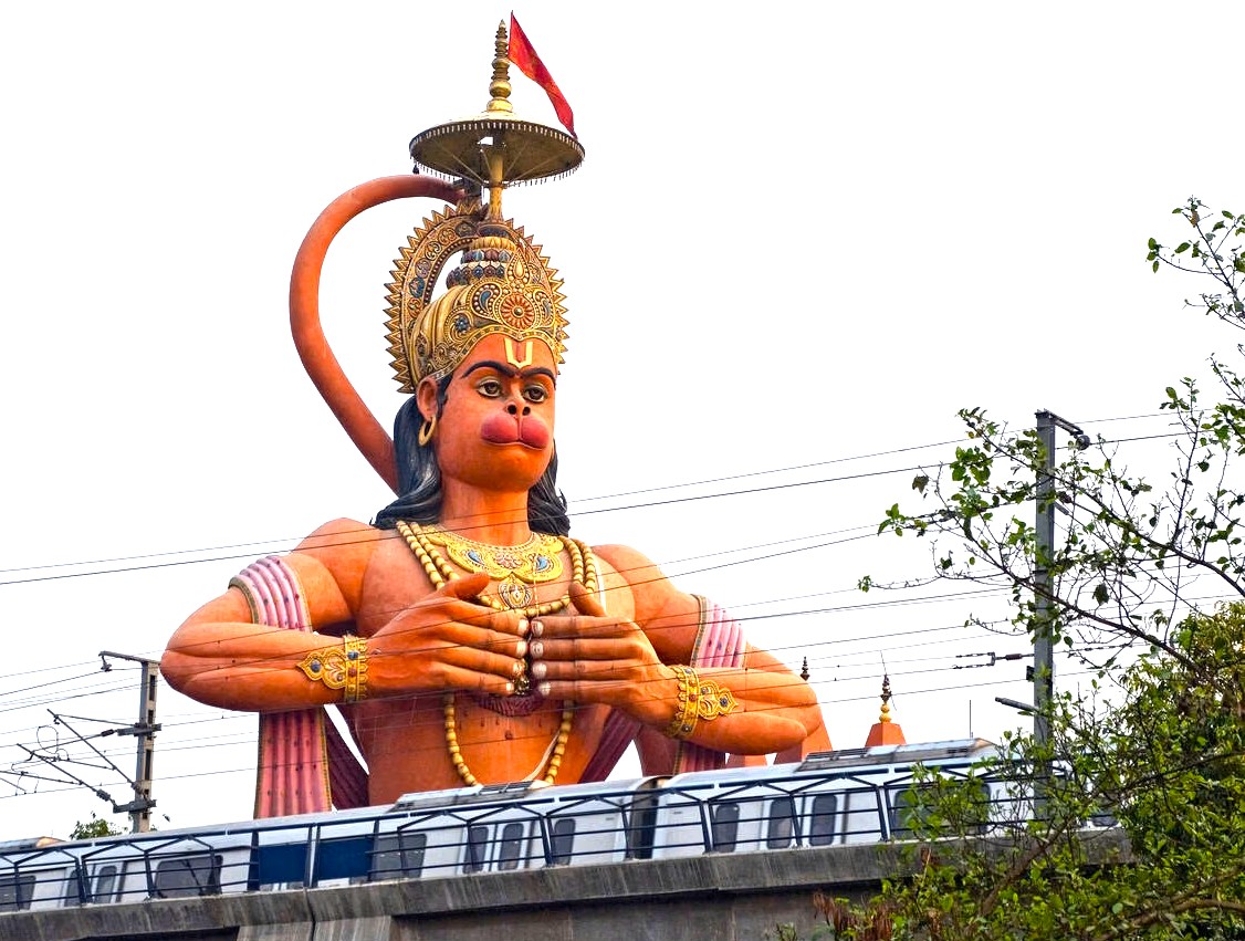 Majestic Hanuman Mandir statue towers over bustling metro tracks in New Delhi, India, symbolizing Hindu devotional fervor, cultural heritage, religious pilgrimage, urban spirituality, architectural craftsmanship, tourism destination, and community reverence.