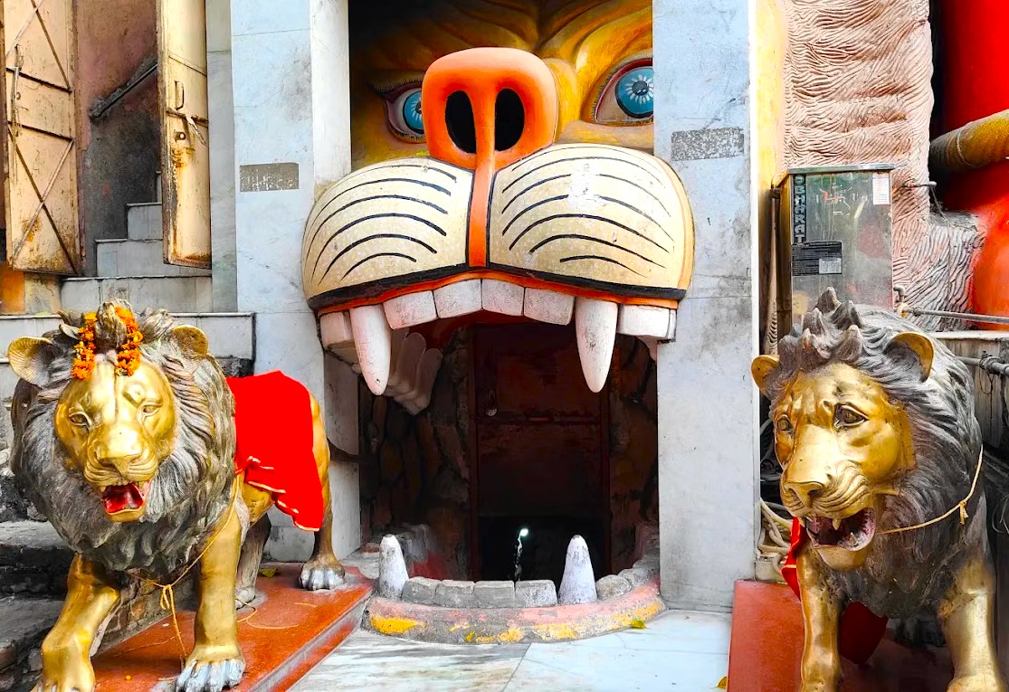 Colorful tiger-faced entrance flanked by golden lion statues at the historic Hanuman Mandir in New Delhi, India, showcasing intricate religious sculpture, vibrant temple architecture and cultural artistry symbolizing divine protection.