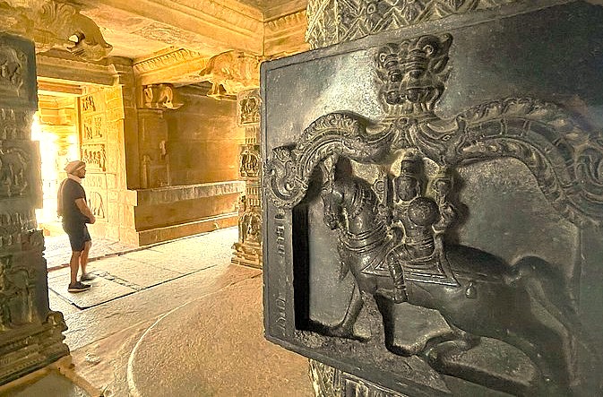 A visitor explores intricate stone carvings inside a temple at the Hampi Unesco site in Karnataka, India, which also features the royal Elephant stables and the historic queens baths.